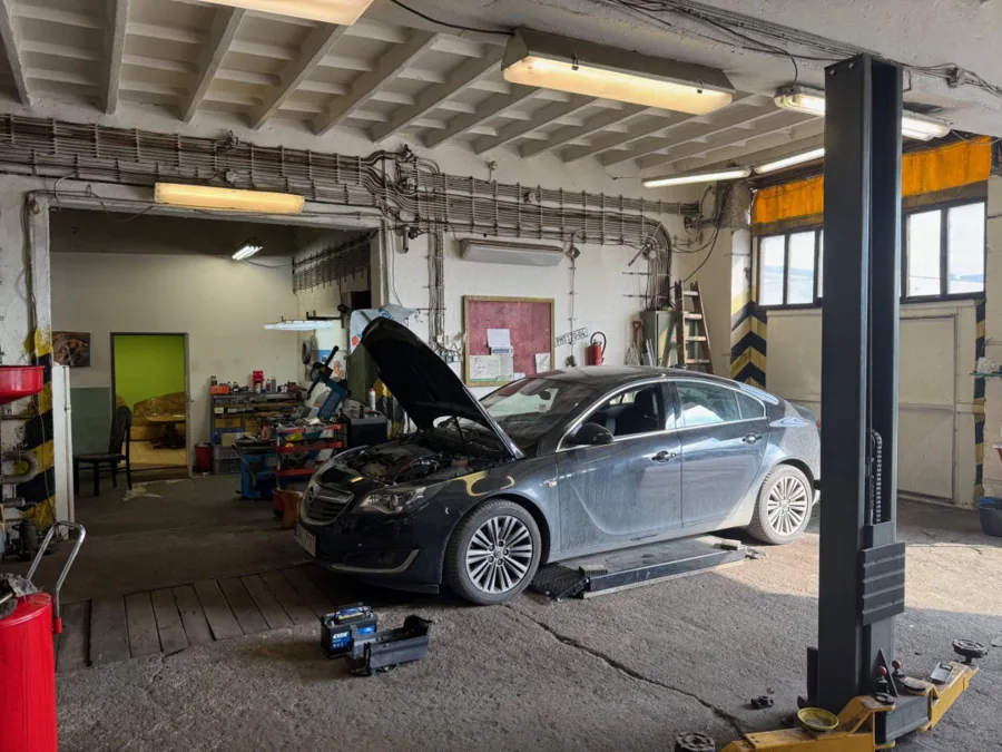 Osobní vůz s otevřenou kapotou při opravě v dílně autoservisu